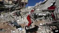 A rescue worker searches the debris with his sniffing dog on the earthquake site in Sarpol-e-Zahab in western Iran, Nov. 14, 2017. 