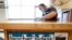 FILE - Des Moines Public Schools custodian Joel Cruz cleans a teacher's desk in a classroom at Brubaker Elementary School in Des Moines, Iowa, July 8, 2020.