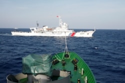 FILE - A ship (top) of the Chinese Coast Guard is seen near a ship of the Vietnam Marine Guard in the South China Sea, about 210 km (130 miles) off shore of Vietnam, May 14, 2014.