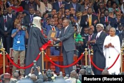 FILE - Kenya's President Uhuru Kenyatta shakes hands with Chief Justice David Maraga as he takes the oath of office during his swearing-in ceremony at Kasarani Stadium in Nairobi, Kenya, Nov. 28, 2017.