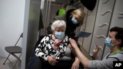 FILE - A woman receives a dose of the AstraZeneca COVID-19 vaccine at the Vaccine.