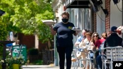 FILE - A member of the wait staff delivers food to outdoor diners along the sidewalk at the Mediterranean Deli restaurant in Chapel Hill, N.C., April 16, 2021. The U.S. economy grew at a brisk 6.4% annual rate last quarter.