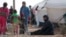 FILE - Iraqi refugees rest near tents in an Iraqi refugee camp in the village of Mabrouka, western countryside of Ras al-Ain, Syria, Jan. 31, 2016. 