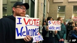 FILE - Residents in support of continued refugee resettlement hold signs at a meeting in Bismarck, N.D., Dec. 9. 2019. 