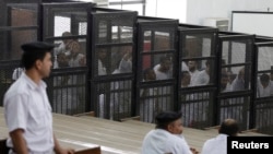 La police surveille des accusés lors d’un procès dans un tribunal du Caire, Egypte, 23 juin 2014.
