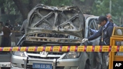 Police and forensic officials examine a damaged Israeli embassy car after an explosion in New Delhi, February 13, 2012.