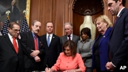 House Speaker Nancy Pelosi signs the resolution to transmit the two articles of impeachment against President Donald Trump to the Senate for trial on Capitol Hill in Washington, Jan. 15, 2020. 