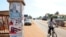 A man rides past a pillar featuring posters of the ruling party presidential candidate, incumbent President John Mahama, and opposition candidate Nana Akufo-Addo in Accra, Oct. 23, 2012.