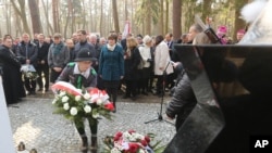 A girl scout lays a wreath at the central monument of a cemetery near the village of Jagiella, in southern Poland, Thursday, March 17, 2016 during ceremonies remembering the Ulma family and eight Jews they were sheltering during Holocaust, all of whom wer