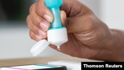 FILE - A person uses Ellume's first over-the-counter coronavirus disease (COVID-19) antigen test, which can be used at home, in this undated image. (Ellume/Handout via Reuters)