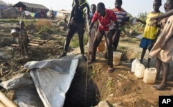 FILE - Displaced people draw water from a hole dug in the ground, in the United Nations camp for displaced people in the capital Juba, South Sudan, Jan. 19, 2016.