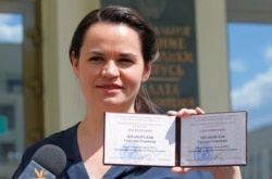 FILE - Presidential candidate Svetlana Tikhanovskaya shows her registration certificate as she leaves the central election commission in Minsk, Belarus, July 14, 2020.