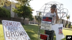Surrounded by barbed wire, Jorge Mendez joins others from Promise Arizona to protest the upcoming U.S. Supreme Court decision on Arizona's immigration law SB1070 at a vigil set up in front of the Capitol in Phoenix,June 22, 2012.