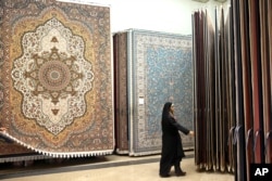FILE - An Iranian female customer looks at the carpets in Tehran's old main bazaar, March 18, 2014. Iran's famed carpet weavers are busy following the country’s historic nuclear deal in July, anticipating a boost in exports as sanctions are to be lifted soon.