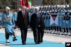 FILE - Turkey's President Recep Tayyip Erdogan, left, and Iran's President Hassan Rouhani inspect a military honour guard during a welcome ceremony in Ankara, Turkey, April 16, 2016.