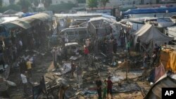 Palestinians look at the damage after an Israeli strike hit a tent area in the courtyard of Al Aqsa Martyrs hospital in Deir al Balah, Gaza Strip, Oct. 14, 2024. 