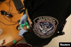 A woman who is seeking asylum has her fingerprints taken by a U.S. Customs and Border patrol officer at a pedestrian port of entry from Mexico to the United States, in McAllen, Texas, May 10, 2017.