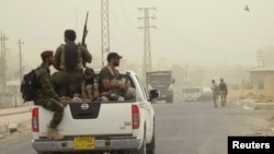 Armed Shi'ite volunteers, travel in a vehicle before taking their positions during a patrol after clashes with militants of the Islamic State, formerly known as the Islamic State in Iraq and the Levant on the outskirts of Samarra in Salahuddin province, July 13, 2014.