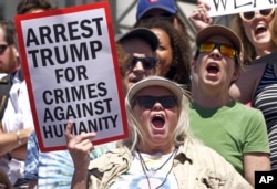 FILE - Activists hold signs to protest the Trump administration's approach to illegal border crossings and separation of children from immigrant parents, June 30, 2018, in Salt Lake City.
