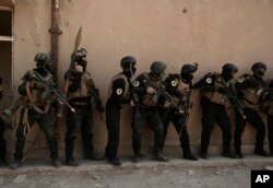 FILE - Soldiers from the 1st Battalion of the Iraqi Special Operations Forces are stacked against a building during a training exercise to prepare for the operation to retake Mosul from Islamic State militants, in Baghdad, Iraq, Aug. 13, 2016.