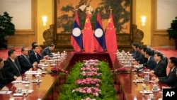 FILE - Chinese President Xi Jinping, left, speaks as Laos' Prime Minister Thongloun Sisoulith, second from right, listens during a meeting at the Great Hall of the People in Beijing, Jan. 6, 2020.