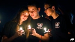Attendees comfort each other at a candlelight vigil for the victims of the shooting at Marjory Stoneman Douglas High School, Feb. 15, 2018, in Parkland, Fla. 