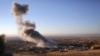 FILE - Smoke believed to be from an airstrike billows over the northern Iraqi town of Sinjar, Nov. 12, 2015. A man on an IS-released video denounced such strikes by "infidels."