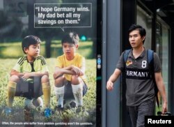 Seorang pria berjalan melewati iklan anti-judi Piala Dunia di sebuah pangkalan taksi di Singapura, 9 Juli 2014. (Foto: Reuters)