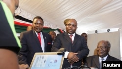 Kenyan President Mwai Kibaki (R) registers as a voter before launching the nationwide, one-month biometric voter registration (BVR) exercise in the capital Nairobi, November 19, 2012, targeting over 18 million voters ahead of the March 4 General Election.