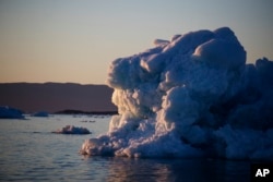 The suns sets against an iceberg floating in the Nuup Kangerlua Fjord near Nuuk in southwestern Greenland, Aug. 1, 2017. Greenland's glaciers have been melting and retreating at an accelerated pace in recent years due to warmer temperatures.