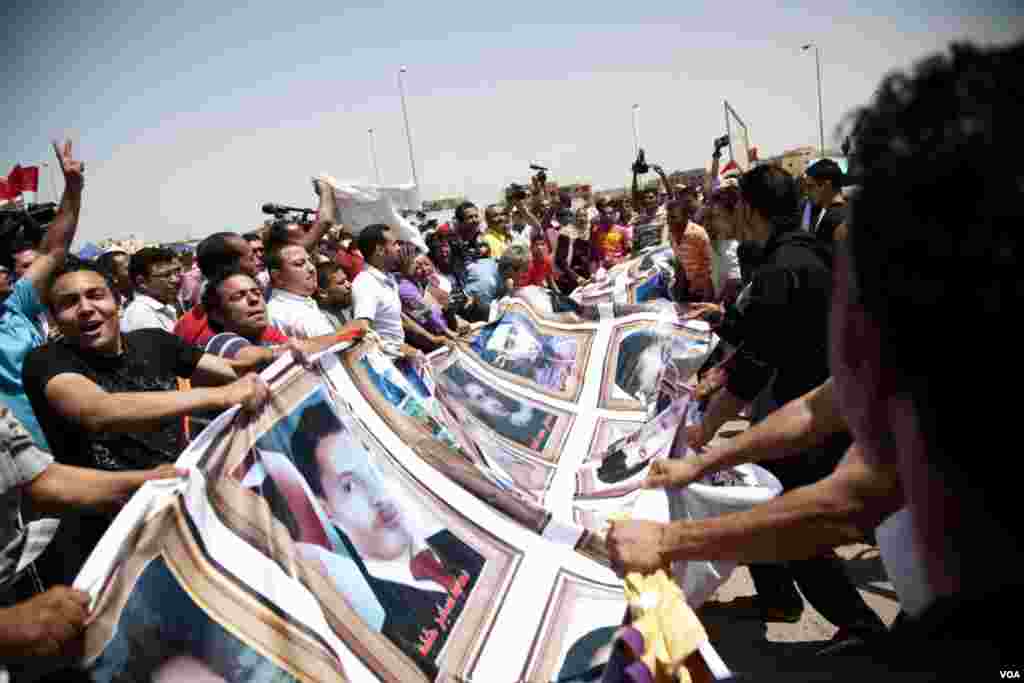 The crowd displays a banner with photos of those killed in the uprising in Cairo, June 2, 2012. (VOA/Y. Weeks)