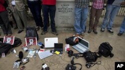 FILE - Journalists stand by the tools of their trade near the Mexican border as they protest violence against journalists by a sign that reads in Spanish 'Limit of the Mexican Republic' in Tijuana, Mexico, Aug. 7, 2010.