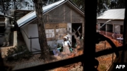 Health workers are seen through a bullet hole left in the window of an Ebola treatment center, which was attacked in early on March 9, 2019, in Butembo, Democratic Republic of the Congo.
