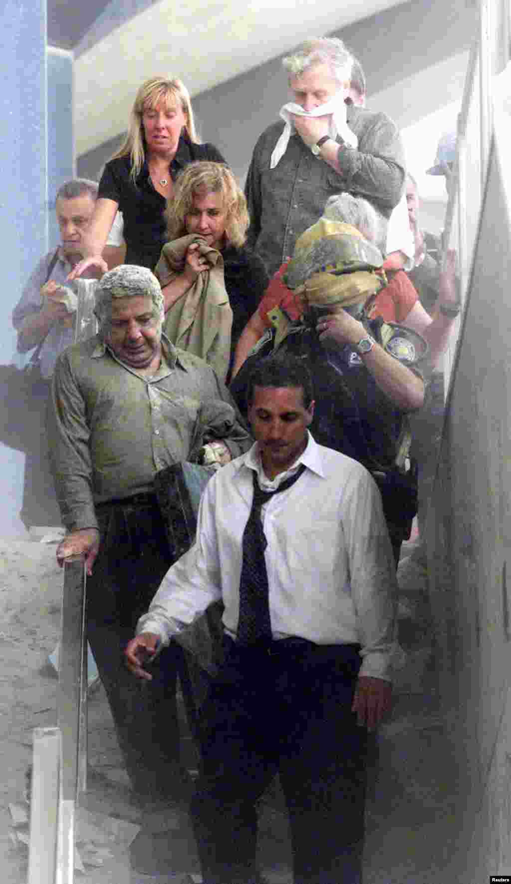 People walk away from the World Trade Center tower. Three hijacked planes crashed into U.S. landmarks, destroying both of New York&#39;s mighty twin towers and plunging the Pentagon in Washington into flames.