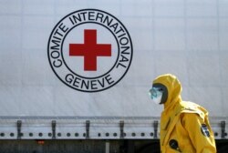 Seorang petugas mengenakan alat pelindung saat ikut dalam konvoi truk desinfeksi Komite Palang Merah Internasional (ICRC) dan Perserikatan Bangsa-Bangsa (PBB). (Foto: dok).