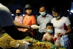 FILE - A family wearing protective masks purchases food at a market in Yangon, Myanmar, Feb. 3, 2020.