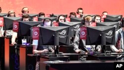 FILE - In this Aug. 20, 2019 file photo, gamers play the latest video games from Electronic Arts at the Gamescom in Cologne, Germany. 