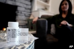 A prescription bottle named osimertinib (brand name: Tagrisso) is seen on a table as Jill Feldman looks at her prescription bottle at her home in Deerfield, Ill., Friday, Jan. 19, 2024. (AP Photo/Nam Y. Huh)
