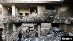 Guards stand on the rubble of a house hit by Saudi-led air strikes in Sanaa, Yemen, January 18, 2022. 