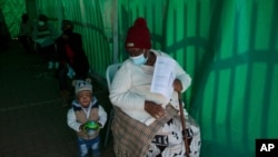 An elderly woman with a young child queues to receive her Pfizer COVID-19 vaccine at a clinic at Orange Farm, near Johannesburg, South Africa, June 3, 2021. 