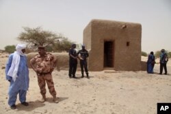 FILE - In this photo taken July 18, 2015, people attending a ceremony stand near a mausoleum that was restored in Timbuktu, Mali.
