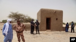 FILE - In this photo taken July 18, 2015, people attending a ceremony stand near a mausoleum that was restored in Timbuktu, Mali. 