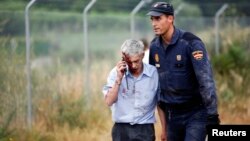 An injured man, identified by Spanish newspapers El Pais and El Mundo as the train driver Francisco Jose Garzon, is helped by a policeman after a train crashed near Santiago de Compostela, northwestern Spain, July 24, 2013.