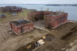Workers wearing personal protective equipment bury bodies in a trench on Hart Island, Thursday, April 9, 2020, in the Bronx borough of New York, April 9, 2020.