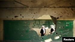 Palestinian students look inside a classroom that witnesses said was shelled by Israel during its offensive, on the first day of the new school year east of Gaza City September 14, 2014.