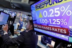 FILE - The rate decision of the Federal Reserve is shown on a television on the floor of the New York Stock Exchange, June 14, 2017.
