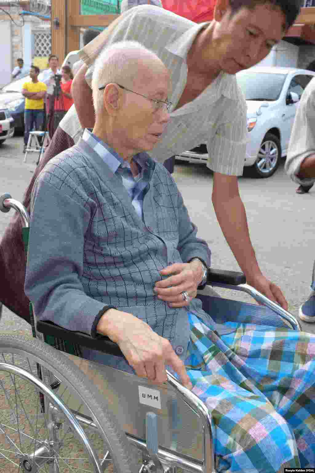 An elderly voter is assisted in reaching his polling station in Yangon, Nov. 8, 2015.