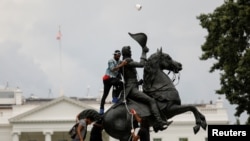 FILE - Protesters attach a chain to the statue of President Andrew Jackson to pull down in the middle of Lafayette Park outside the White House as someone throws a roll of toilet paper during racial inequality protests in Washington, D.C., June 22, 2020.