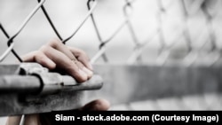 反映人口贩运问题的图库照片，一名女性手握铁丝网。(2017年12月2日)