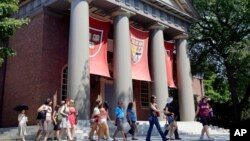 FILE - A tour group walks through the campus of Harvard University in Cambridge, Mass, Aug. 30, 2012. The Justice Department has sided with Asian-American students suing Harvard University over the Ivy League school's consideration of race in its admissio
